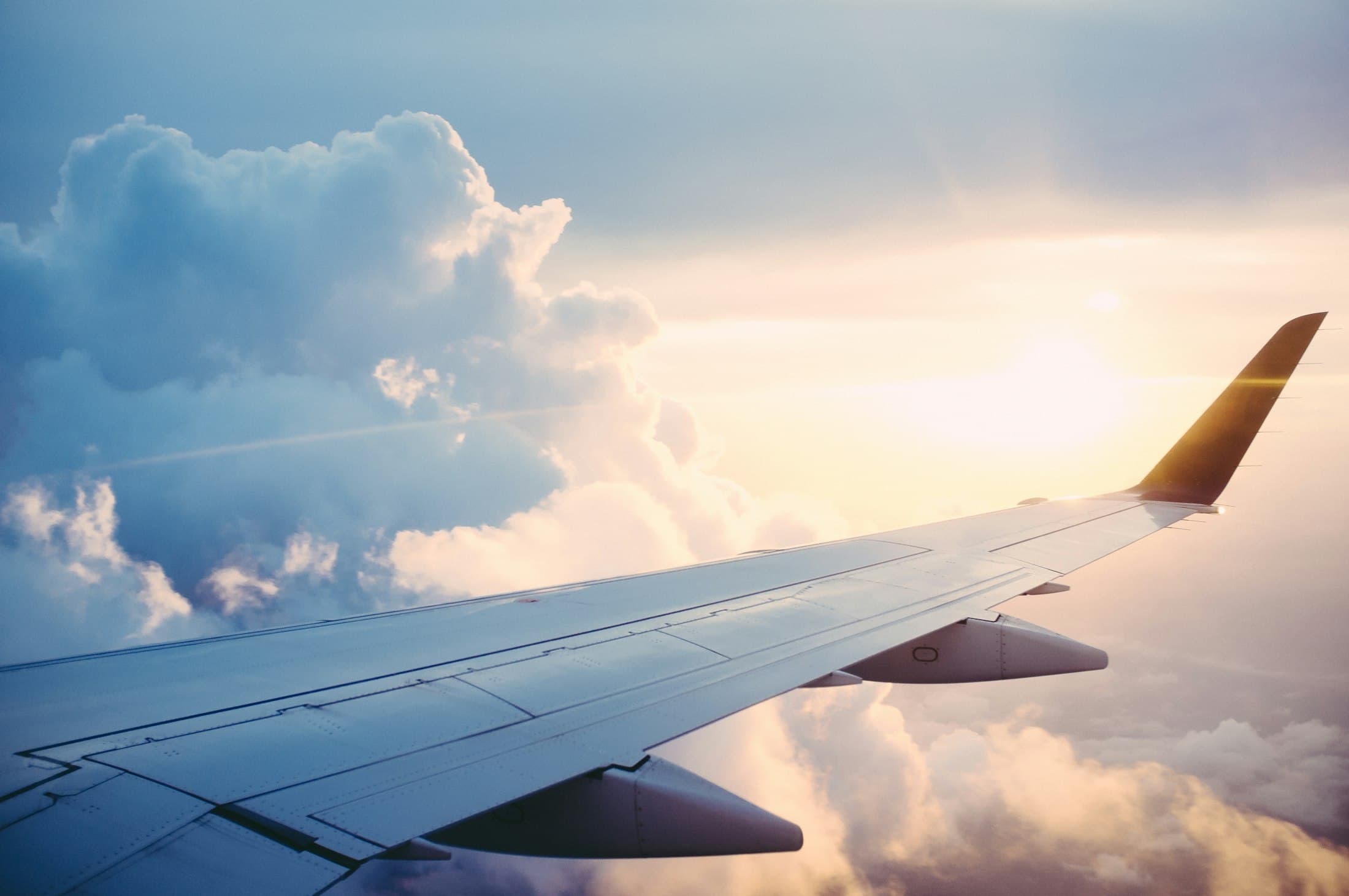 Airplane wing above golden clouds at sunset